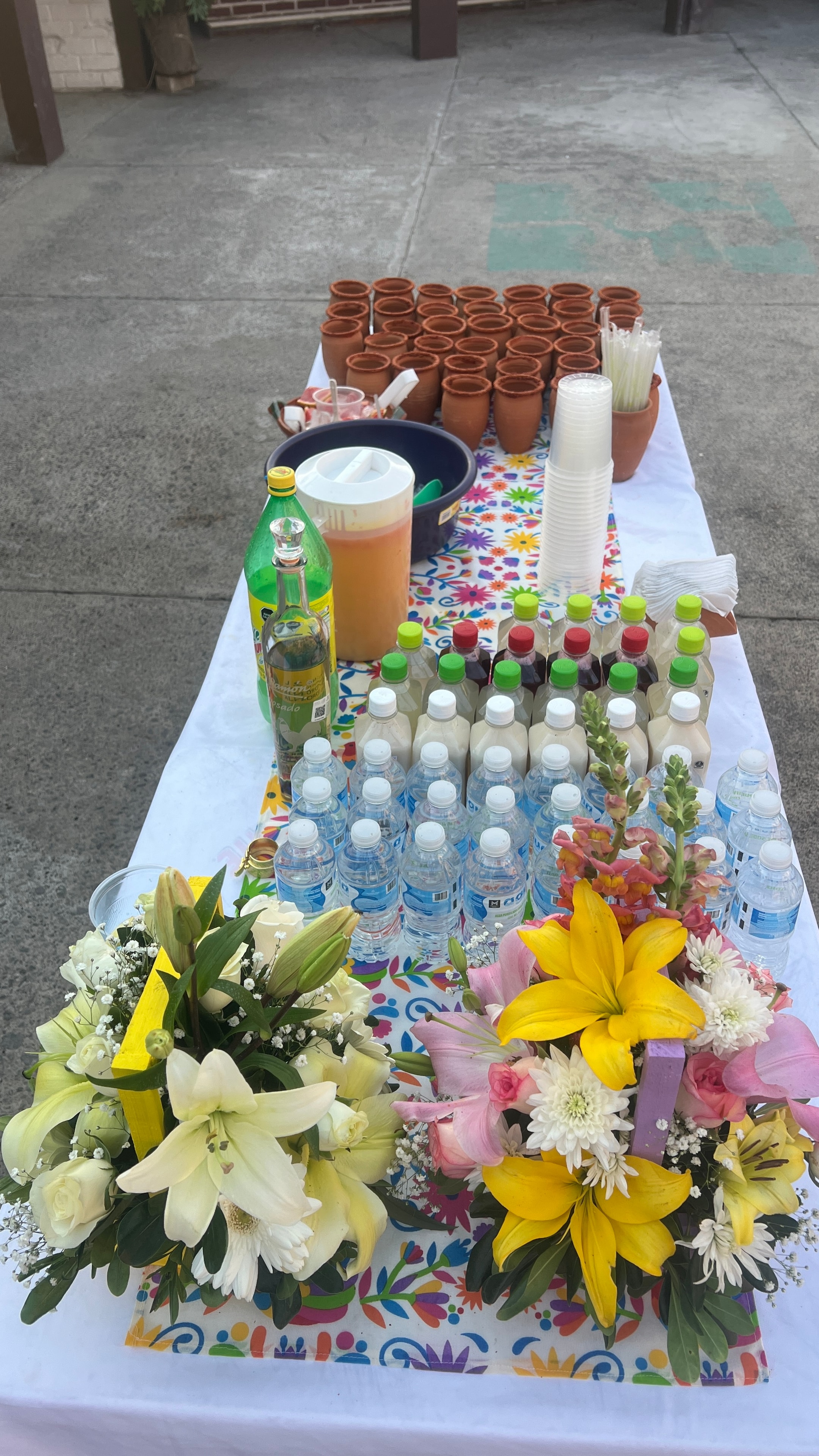 Mesa de bebidas decorada con flores y aguas frescas