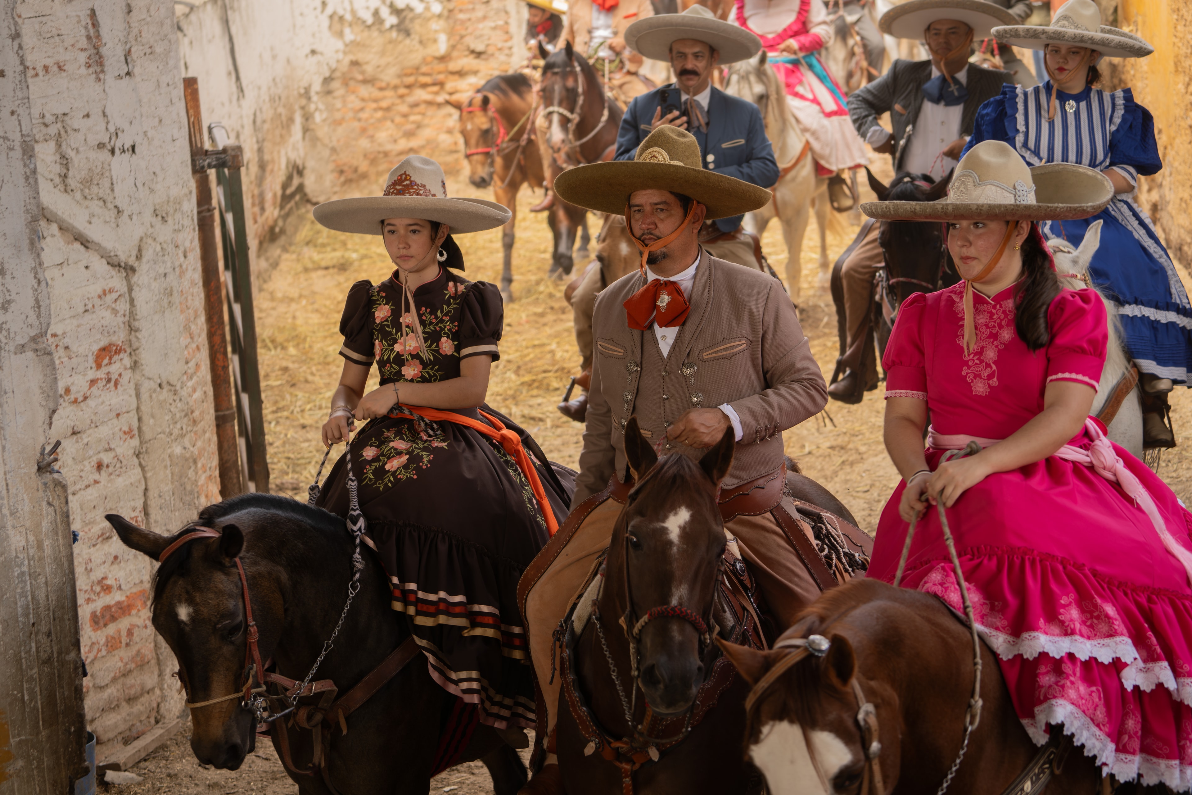 Procesión de charros y escaramuzas en trajes típicos por callejón colonial