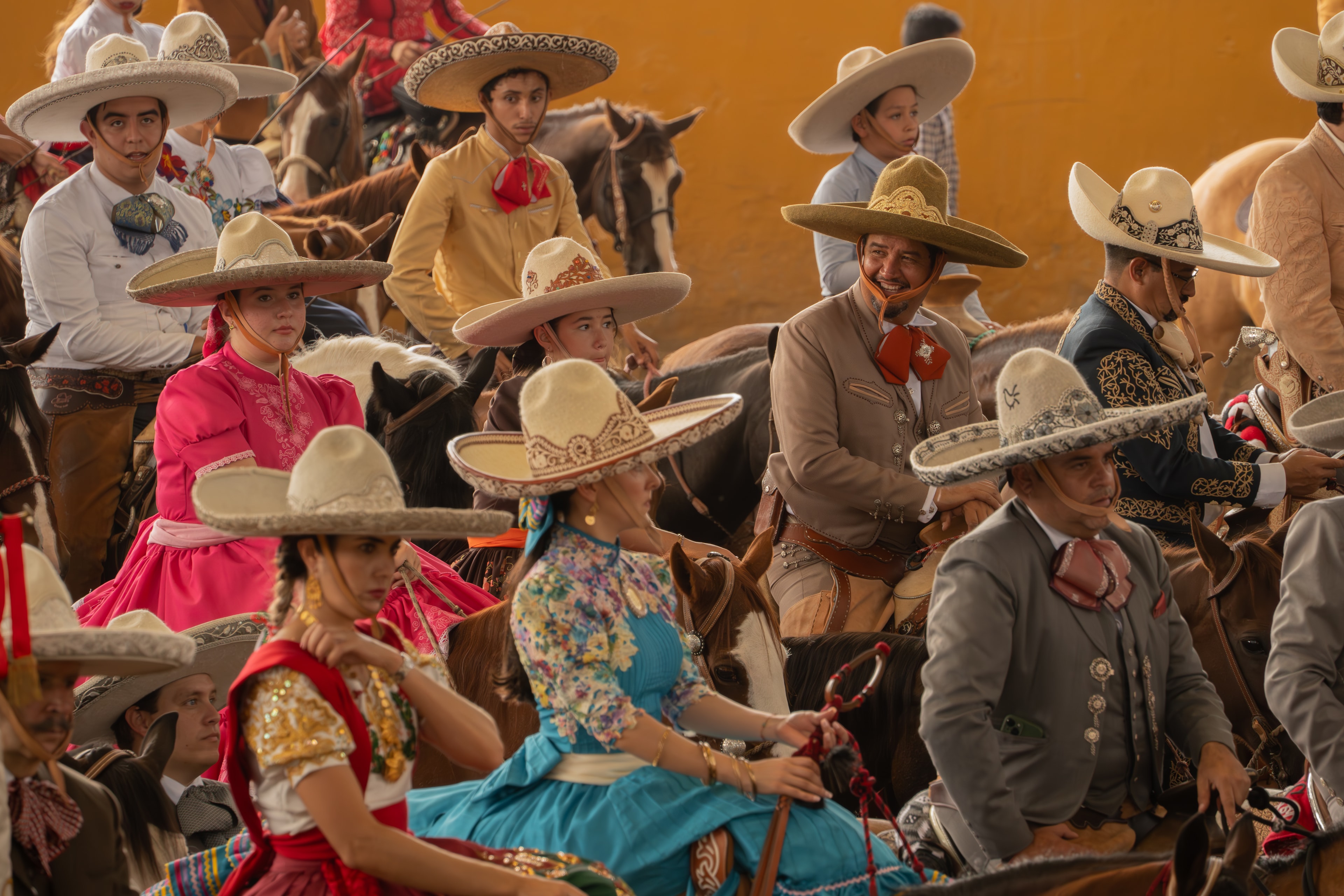 Grupo de charros y escaramuzas sonriendo a caballo en el Lienzo Charro