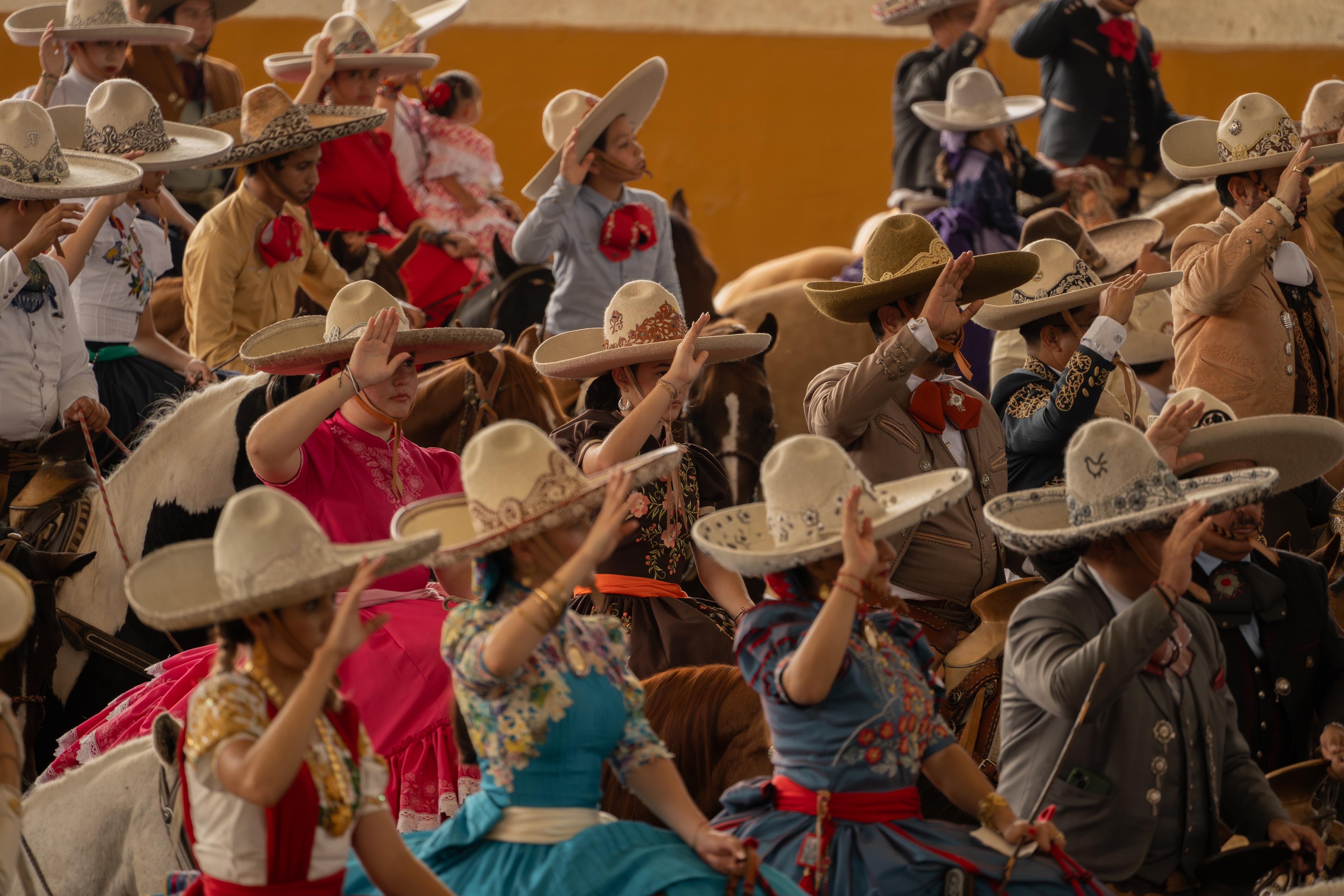 Charros y escaramuzas saludando con el sombrero en el Lienzo Charro