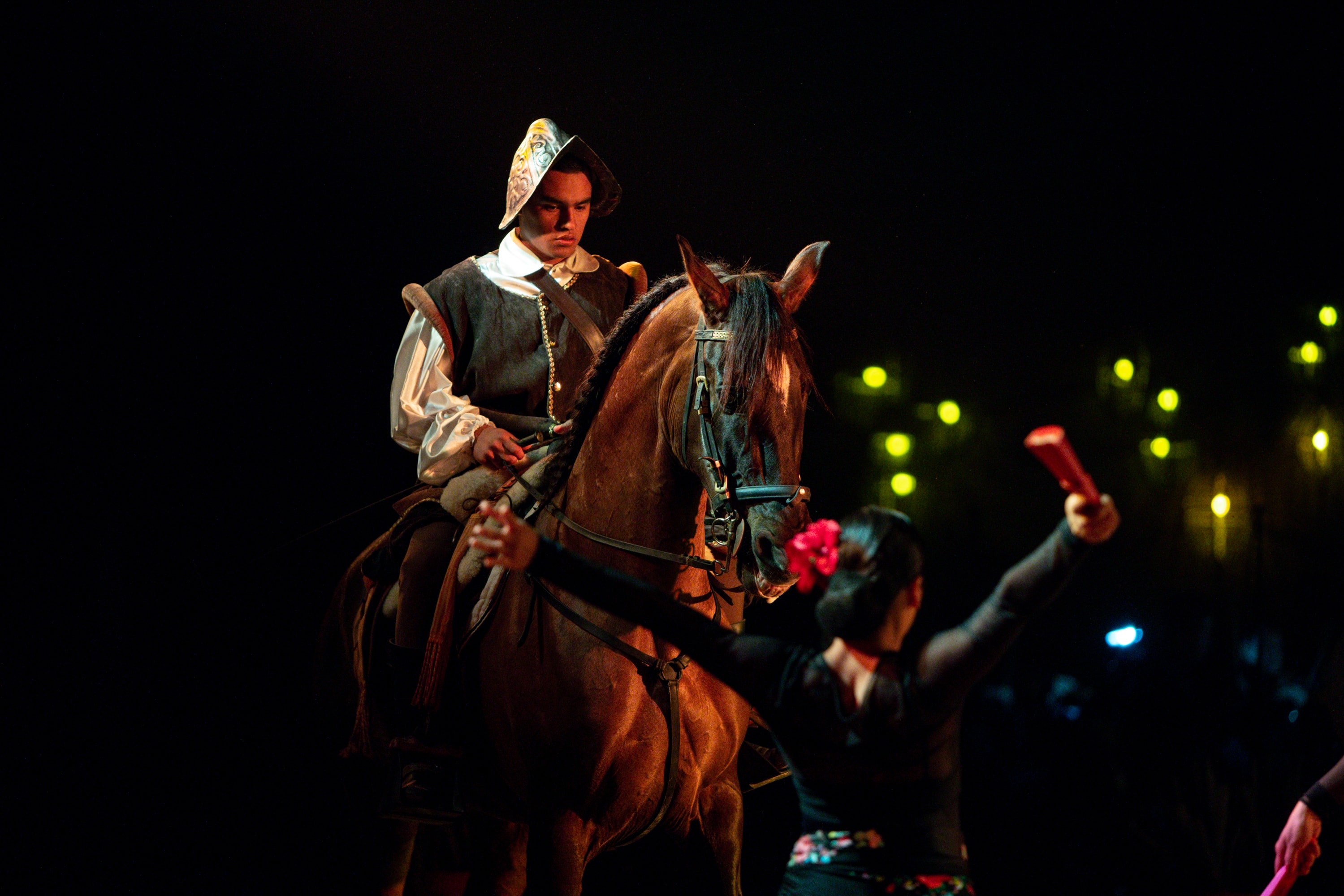 Charro a caballo con máscara durante espectáculo nocturno en el Lienzo Charro