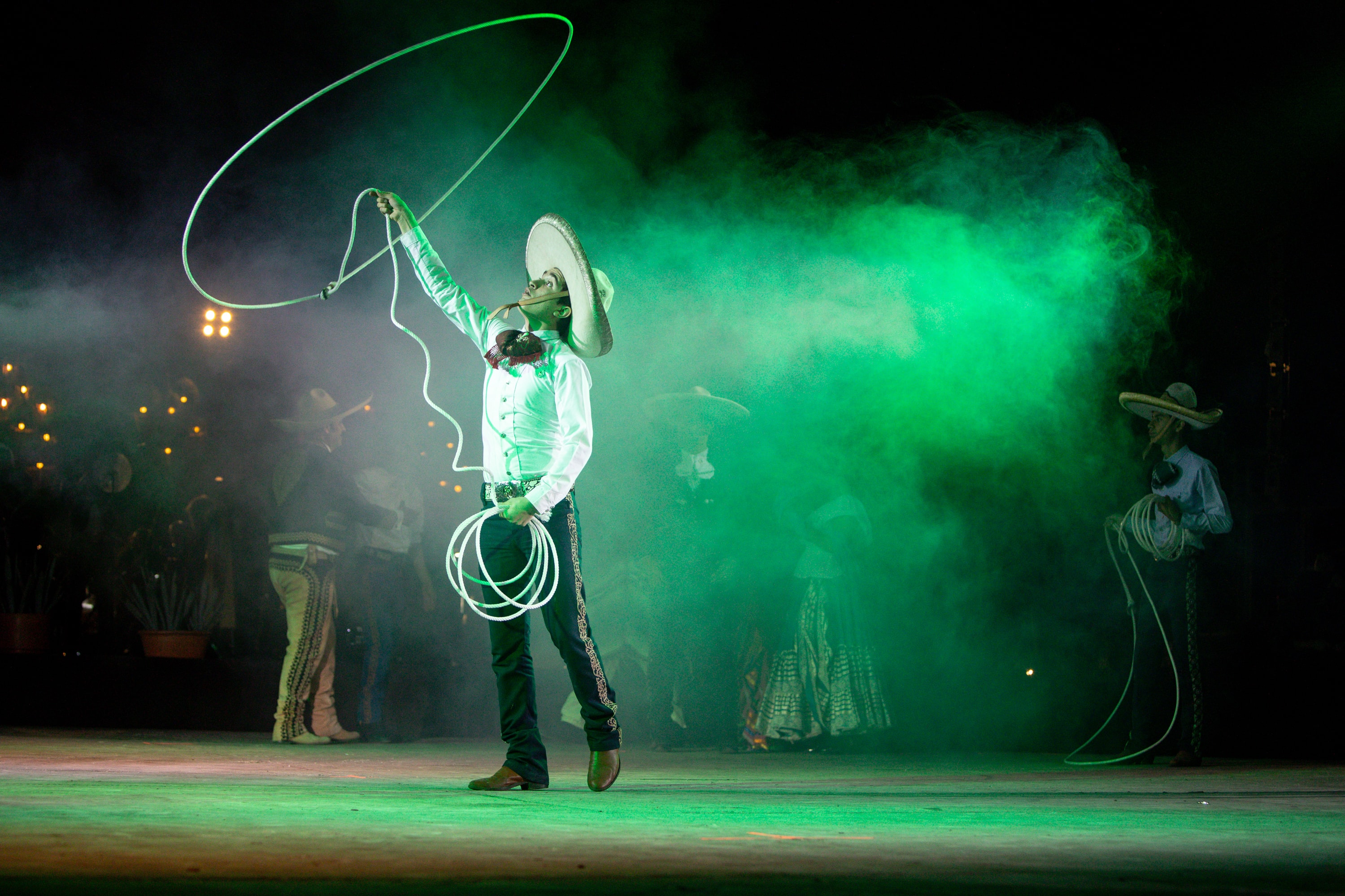 Charro lanzando reata neón verde con humo en el Lienzo Charro
