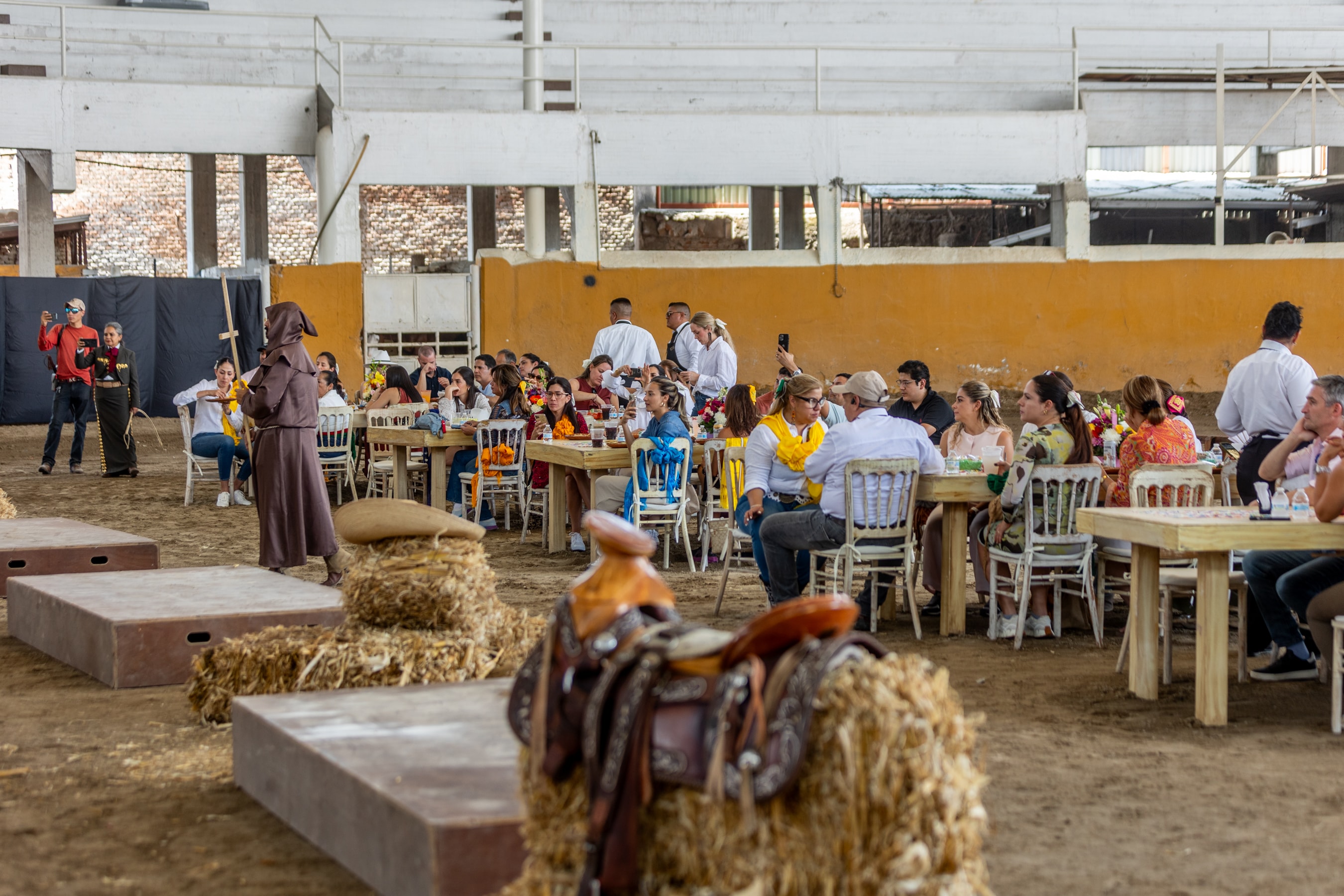 Grupo de invitados sentados en el Lienzo Charro con pacas de paja y silla de montar